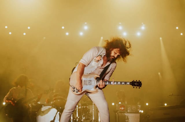 Guitarist performing under golden stage lights at Bourbon & Beyond