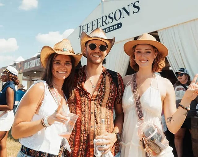Three friends smiling together in the bourbon and culinary area at Bourbon & Beyond